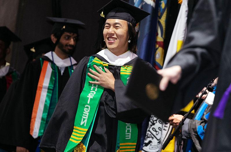 A student wearing a "first gen" stole graduates from college